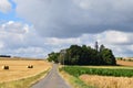 country road into Fraukirch between harvested grain fields and green corn