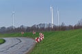 Country Road, green meadow and three wind turbines on the blue sky