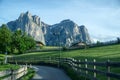 country road through green meadows below jagged mountain peaks