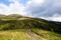 Country road in green mountains. Background with white clouds Royalty Free Stock Photo