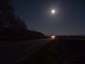Country Road Illuminated by the Headlights of an Approaching Car Royalty Free Stock Photo