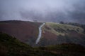 Country road lane leading to top of deserted hill mountain clouds foggy mist view baron landscape Peak District countryside dark Royalty Free Stock Photo