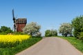 Country road by an old windmill in a colorful spring season land Royalty Free Stock Photo