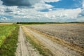 Country road, plowed field and clouds in the sky