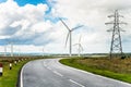Wind farm along a country road on a partly cloudy summer day Royalty Free Stock Photo
