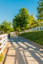 Country road surrounded the horse farms with evening fence shadows. Royalty Free Stock Photo