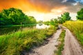 Country road to sun along river at sunset Royalty Free Stock Photo