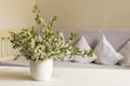 Country style living room. Cherry flower in white pot on wooden table. Still life