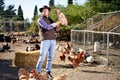 Countryman holding brown chicken in hands in hen house