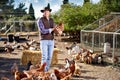 Countryman holding brown chicken in hands in hen house