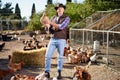 Countryman holding brown chicken in hands in hen house