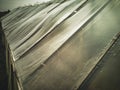 Countryside farm worn plastic film greenhouse moving in strong wind, dramatic grayscale view with dark sky background