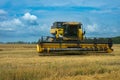 countryside harvest: yellow combine harvester collecting wheat under a clear blue sky