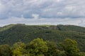 Countryside with a hill covered with lush green trees with a windmill with a cloud covered sky Royalty Free Stock Photo