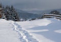 Countryside hills, groves and farmlands in winter remote alpine mountain village. Freshly trodden hiking trail path