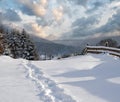 Countryside hills, groves and farmlands in winter remote alpine mountain village. Freshly trodden hiking trail path
