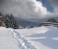 Countryside hills, groves and farmlands in winter remote alpine mountain village. Freshly trodden hiking trail path