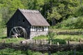 Countryside house with wooden mill amid green trees and lush nature. Wooden or half timbered farmer factory conveys bio farm