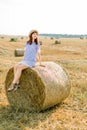 Countryside landscape of farm wheat field at summer sunset. Pretty young happy Caucasian woman in straw hat and blue Royalty Free Stock Photo