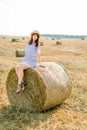Countryside landscape of farm wheat field at summer sunset. Pretty young happy Caucasian woman in straw hat and blue Royalty Free Stock Photo