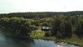 Countryside river with a wooden pier and a house among trees. Stock footage. Aerial of the ecological area with a