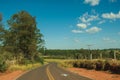 Countryside road on landscape covered by meadows and trees