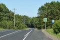 Countryside road surrounded by trees, road signs and powerline poles under a clear blue sky Royalty Free Stock Photo