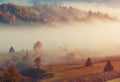 Countryside rural mountain hill landscape with haystack and morning fog. Royalty Free Stock Photo