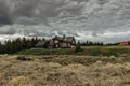 Countryside scene with wooden house and cloudy sky on background. Farm house surrounded by trees and fields.Lonely tourist house Royalty Free Stock Photo