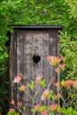 Countryside toilet house with heart shaped hole in the door in the green garden Royalty Free Stock Photo