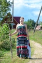 Countrywoman in village standing on rural road with instruments