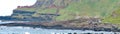 Panoramic of Tourists exploring the unusual rock formations at Giant`s Causeway.