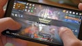 A man holds a smartphone and plays Korean MMORPG Black Desert Online on it, close-up video,