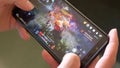 A man holds a smartphone and plays MMORPG Black Desert Online, close-up, illustrative