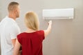 Couple Adjusting Temperature Of Air Conditioner Royalty Free Stock Photo