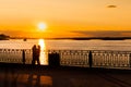 Couple admiring dramatic colorful golden susnet on river at quay