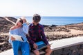 Couple of adults using laptop and talet together with the beach a the background - two people smiling and having fun - man using Royalty Free Stock Photo