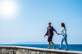 Couple of adults walking together taking their hands with the ocean or sea and beautiful island background - happy vacations Royalty Free Stock Photo