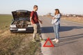 Couple argue on road, have problem with brocken car, being in panic, don`t know what to do, red warning triangle warns other drive