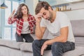 Couple argue. The wife shouted to her desperate husband, sitting on the couch in the living room at home. A man does not