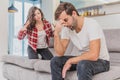 Couple argue. The wife shouted to her desperate husband, sitting on the couch in the living room at home. A man does not