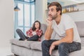 Couple argue. The wife shouted to her desperate husband, sitting on the couch in the living room at home. A man does not