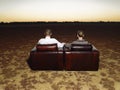 Couple On Armchairs Watching Sunset In Open Plain