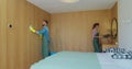 Couple as a professional cleaners in uniform rubbing furniture and wiping dust in the bedroom or hotel room. Cleaning Royalty Free Stock Photo