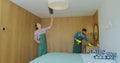 Couple as a professional cleaners in uniform rubbing furniture and wiping dust in the bedroom or hotel room. Cleaning Royalty Free Stock Photo