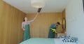 Couple as a professional cleaners in uniform rubbing furniture and wiping dust in the bedroom or hotel room. Cleaning Royalty Free Stock Photo