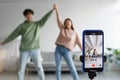 Couple of Asian influencers shooting dance video for social network on cellphone, having fun at home, selective focus Royalty Free Stock Photo