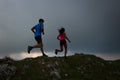Couple of athletes mountain runners train on meadow ridge