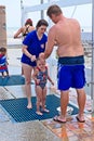 A couple attempts to rinse off their child at a shower at an outdoor beach