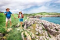 Couple backpacker travelers walk on ocean rocky coast. Asturias.